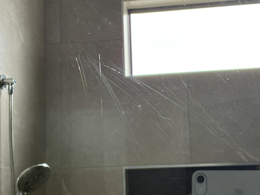 Glass panel or mirror with heavy white scratches before professional polishing
